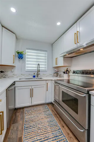 Functional kitchen workspace displaying full-size stainless steel appliances, modern quartz counters, and a window above the deep sink.