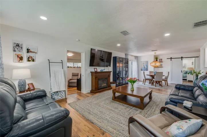 Spacious open-concept living area with warm LVP flooring, recessed lighting.