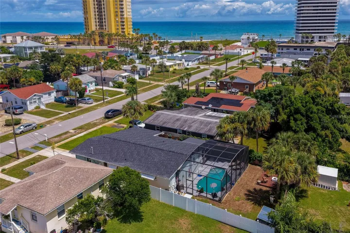 High-angle aerial photo displaying the home’s layout, complete with its screened-in pool area, private yard, and proximity to the coastline.