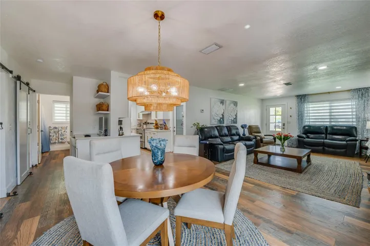 Expansive view of the open-plan main level showing the fluid transition from the dining space through to the main living area and kitchen entry.