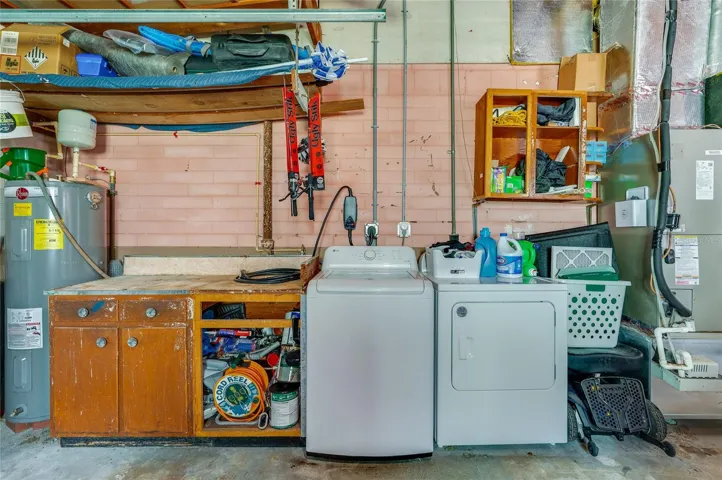 Dedicated utility station in the garage offering a washer and dryer alongside a built-in workbench and open storage shelves.