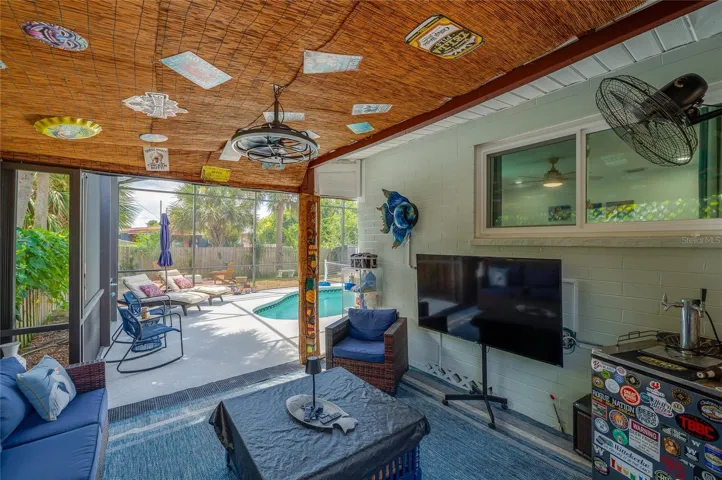 Covered screened porch featuring a woven bamboo ceiling and string lights. The space directly connects to the adjacent enclosed pool deck.