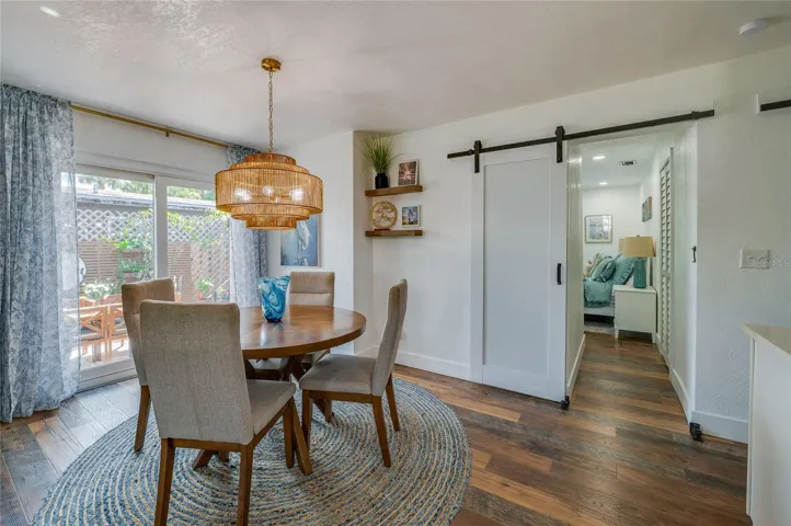 Dedicated dining nook highlighted by a woven pendant light fixture, sliding glass doors to the outside, and a modern white barn door leading down the hallway.