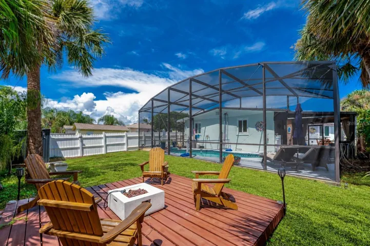 Raised wooden deck in the backyard with the screened pool enclosure and home exterior directly behind it.