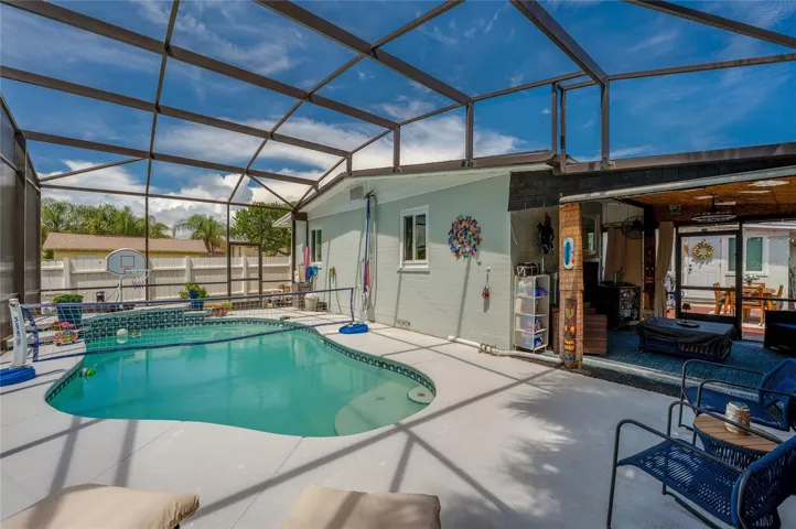 Spacious screened enclosure surrounding a custom in-ground pool with built-in steps. The layout seamlessly blends covered patio living with open-air sunbathing space.