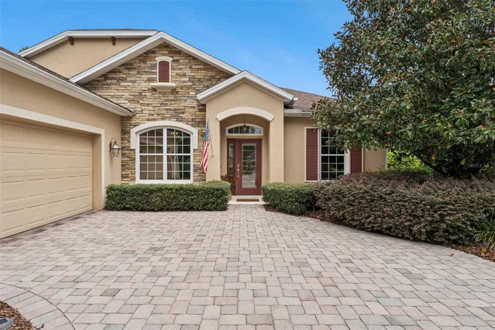 Exterior front of home w/ a stone facade & a leaded glass front door