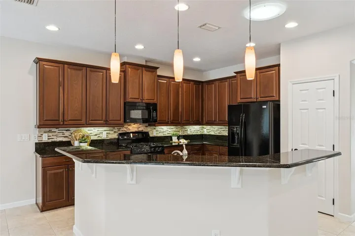 Kitchen breakfast bar w/ pendant lighting above & a solar tube for additional natural light