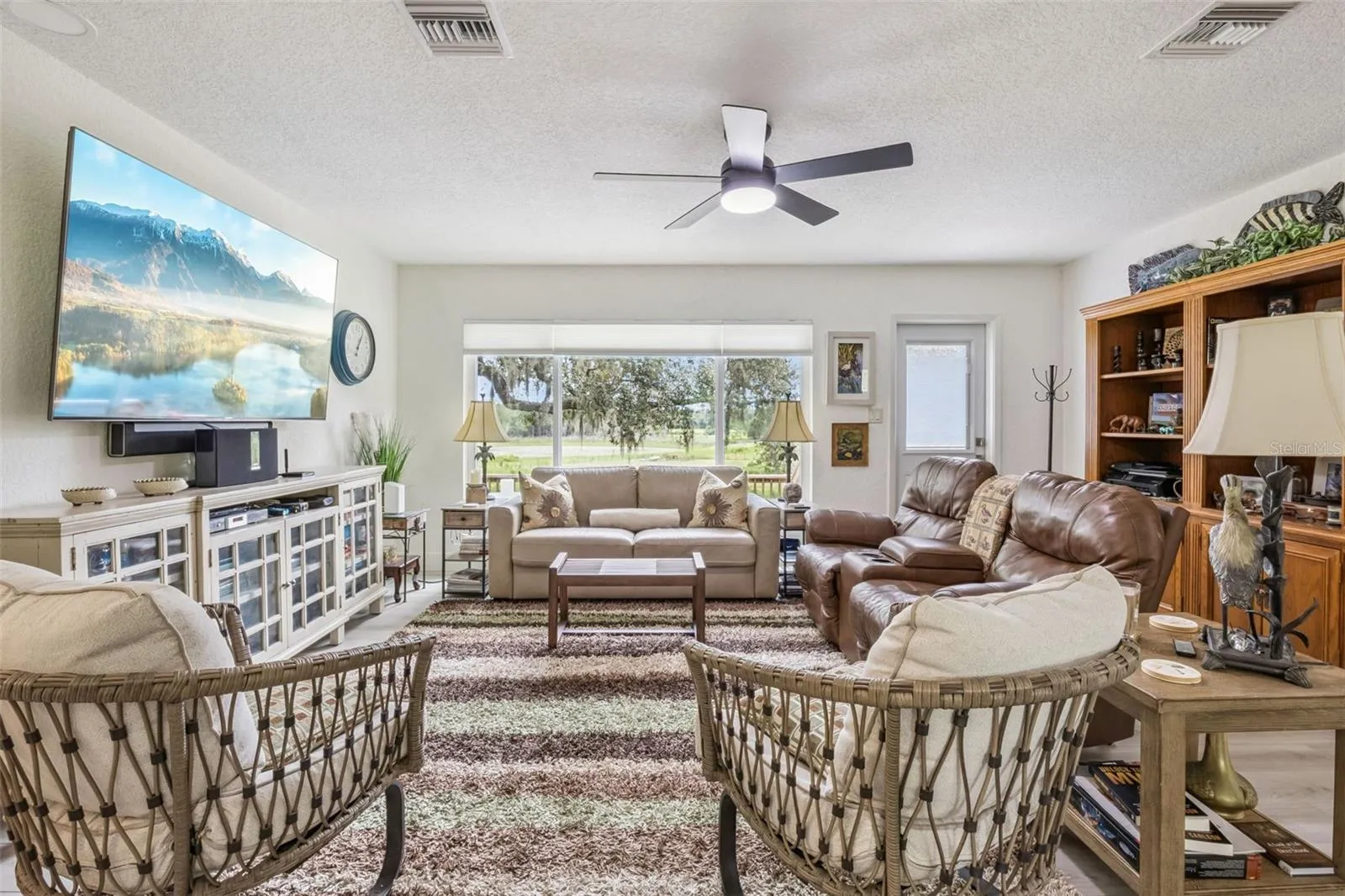 Spacious living room with expansive picture windows framing breathtaking views of rolling green pastures and mature oaks.