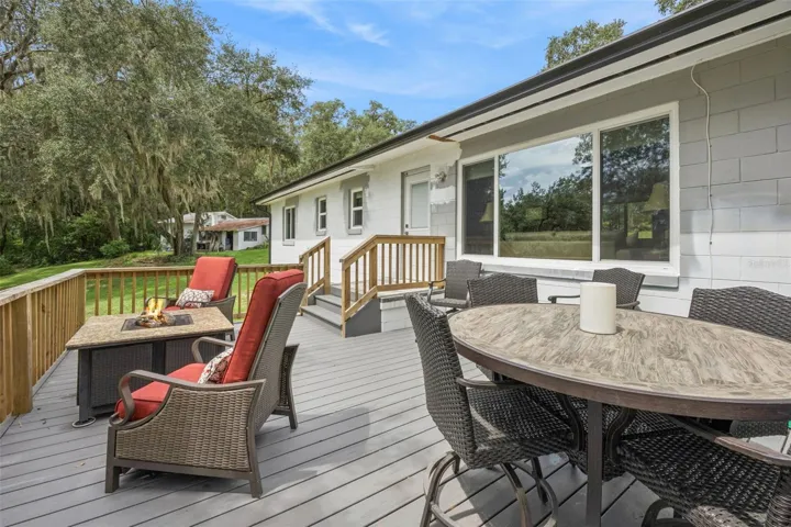 Spacious rear deck with room for outdoor dining and fireside lounging, overlooking the peaceful backyard.