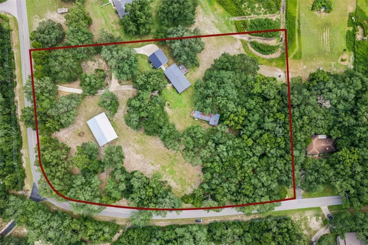 Bird's-eye view showcasing the home's prime position surrounded by mature oaks and open green space.
