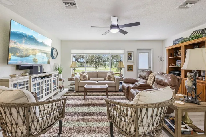 Spacious living room with expansive picture windows framing breathtaking views of rolling green pastures and mature oaks.