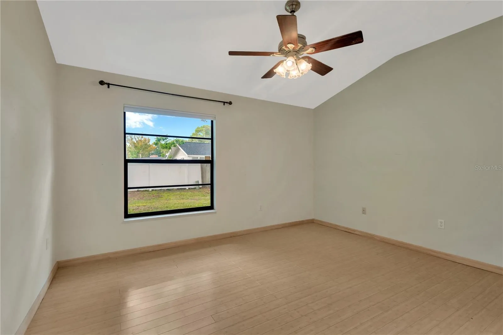 Primary Bedroom with lofted ceiling and ceiling fan, overlooking the private backyard