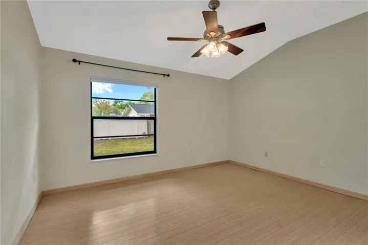 Primary Bedroom with lofted ceiling and ceiling fan, overlooking the private backyard