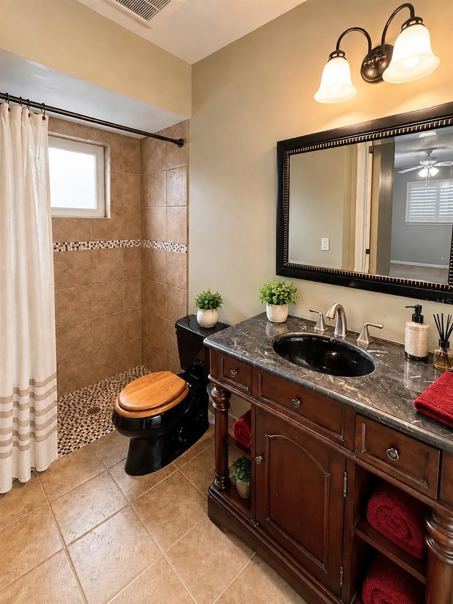 Primary bathroom fully tiles shower , and luxury vanity with marble countertop.