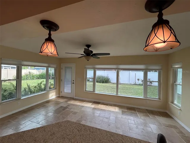 View from kitchen of family room /new impact windows through out the entire home. This room can be enjoyed as a bonus room or every day living .Full of sunshine and views of the private backyard.
