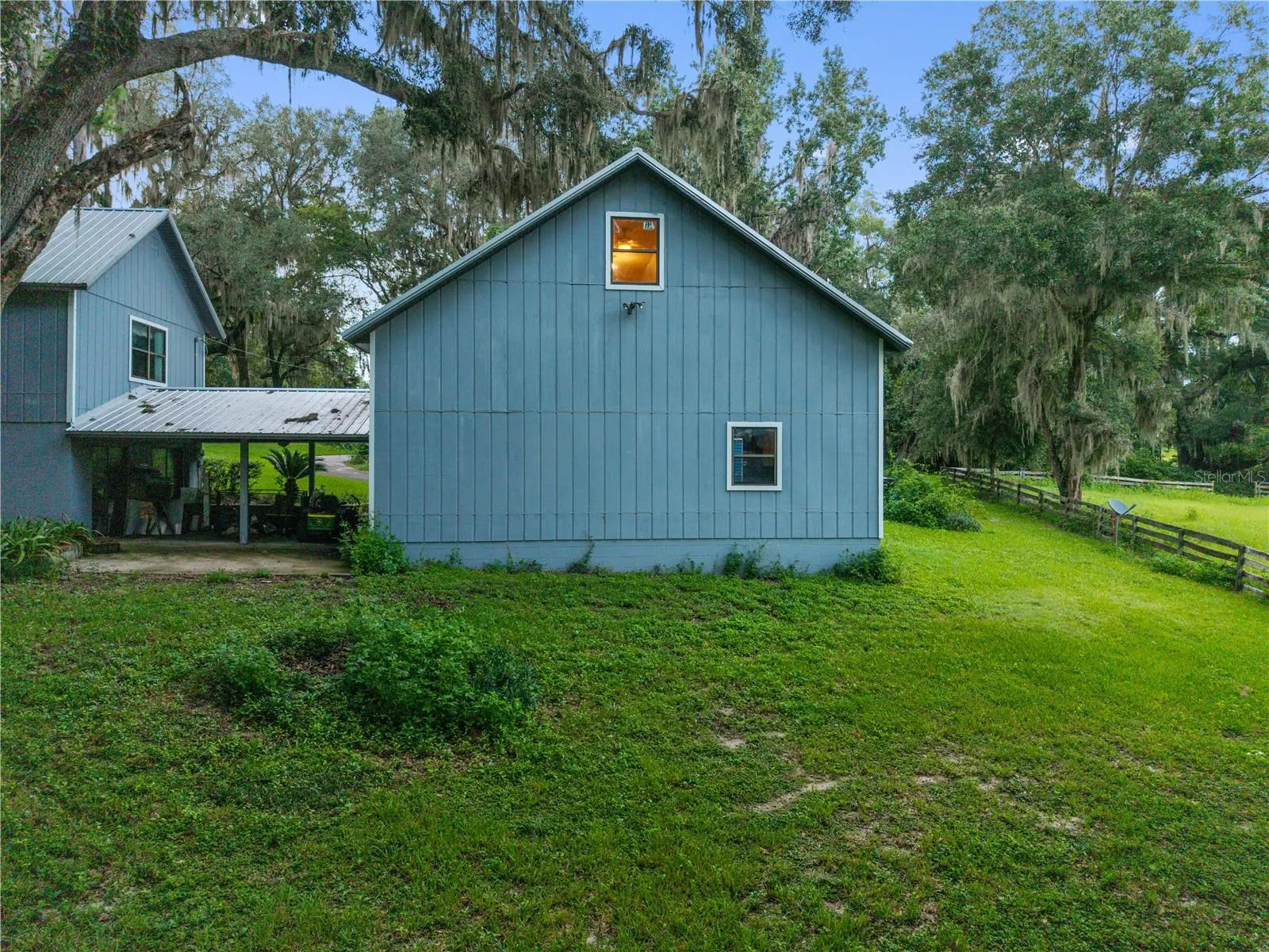 Rear exterior view of the garage and bonus room, surrounded by a spacious yard and mature trees