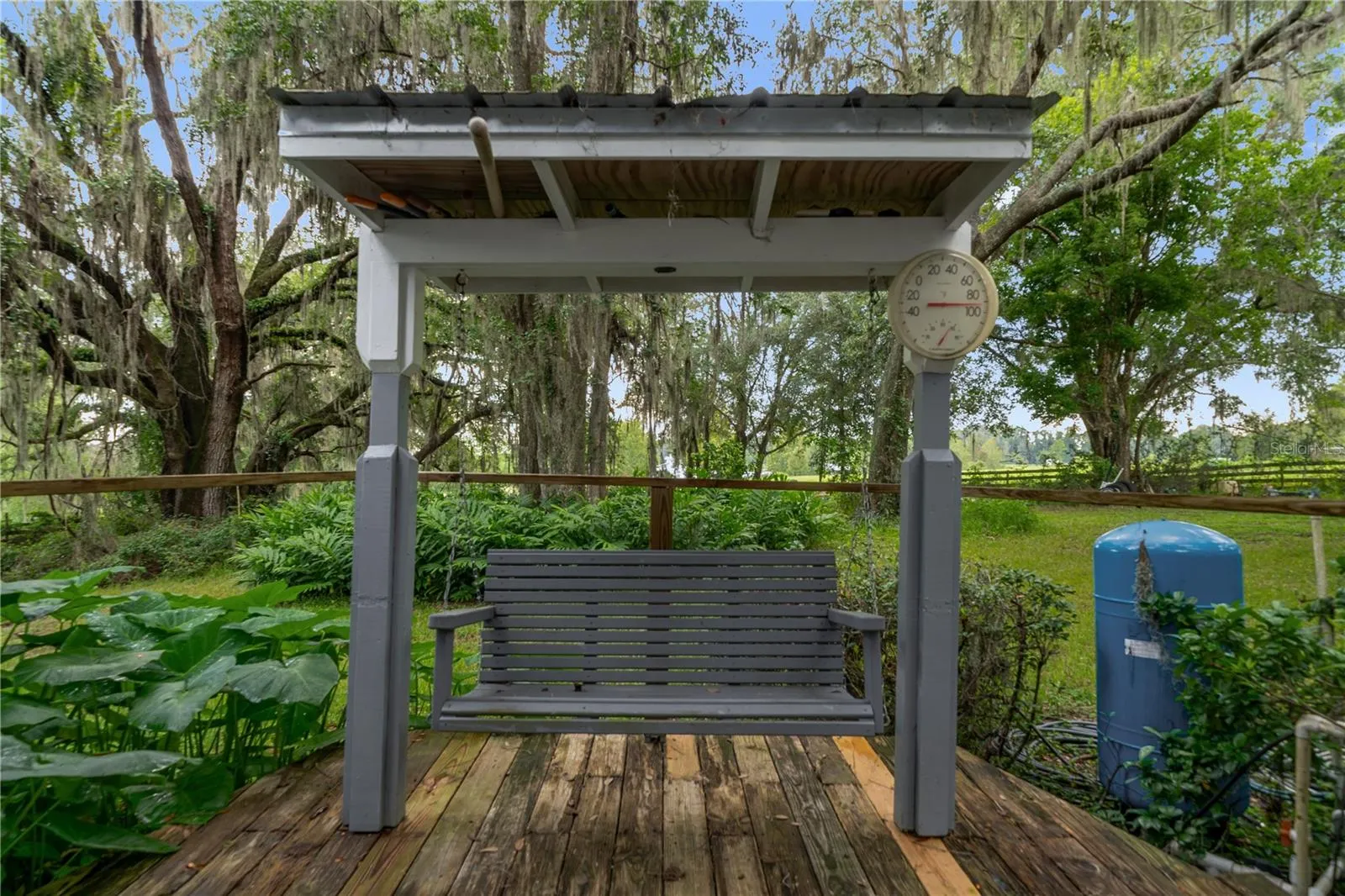 Covered swing overlooking the lush, peaceful backyard surrounded by mature trees and greenery.
