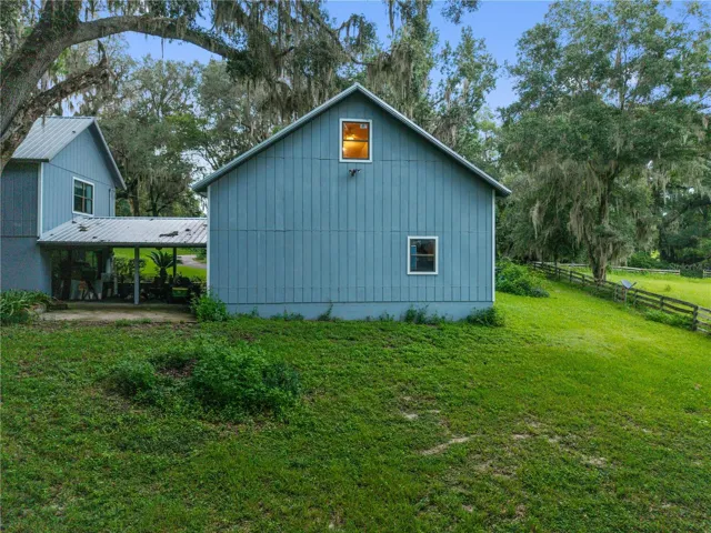 Rear exterior view of the garage and bonus room, surrounded by a spacious yard and mature trees