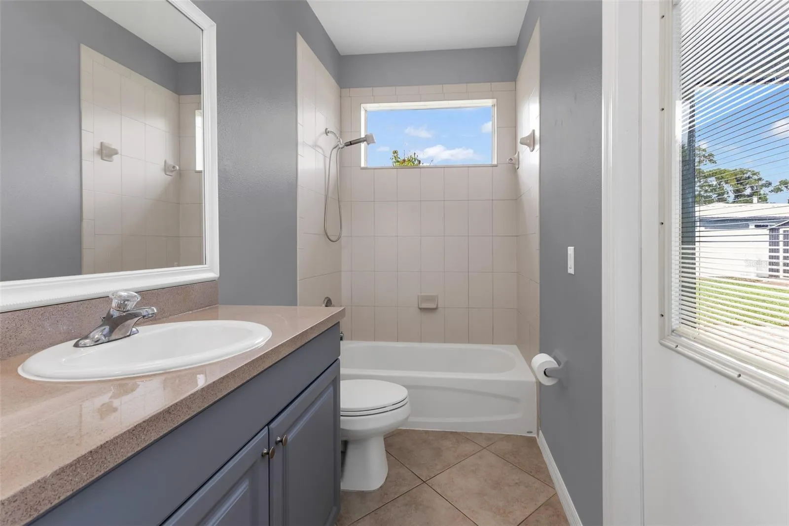 Guest bath with single vanity, shower/tub combo and access to lanai.