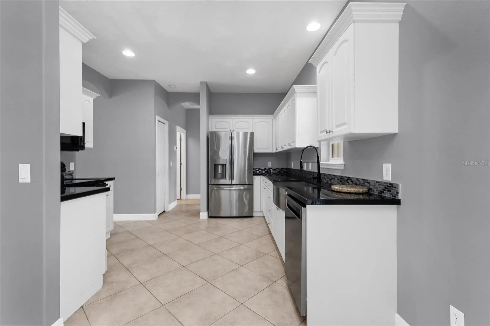 Kitchen features epoxy countertops, glass tile backsplash and plenty of cabinets.