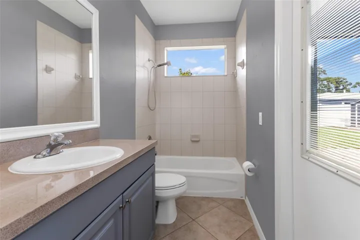 Guest bath with single vanity, shower/tub combo and access to lanai.