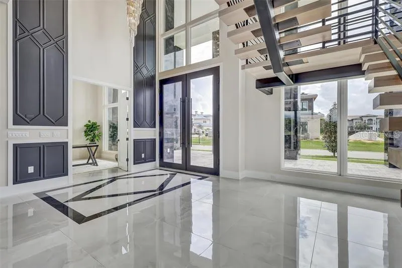 Dramatic entry framed by the floating staircase and two-story windows