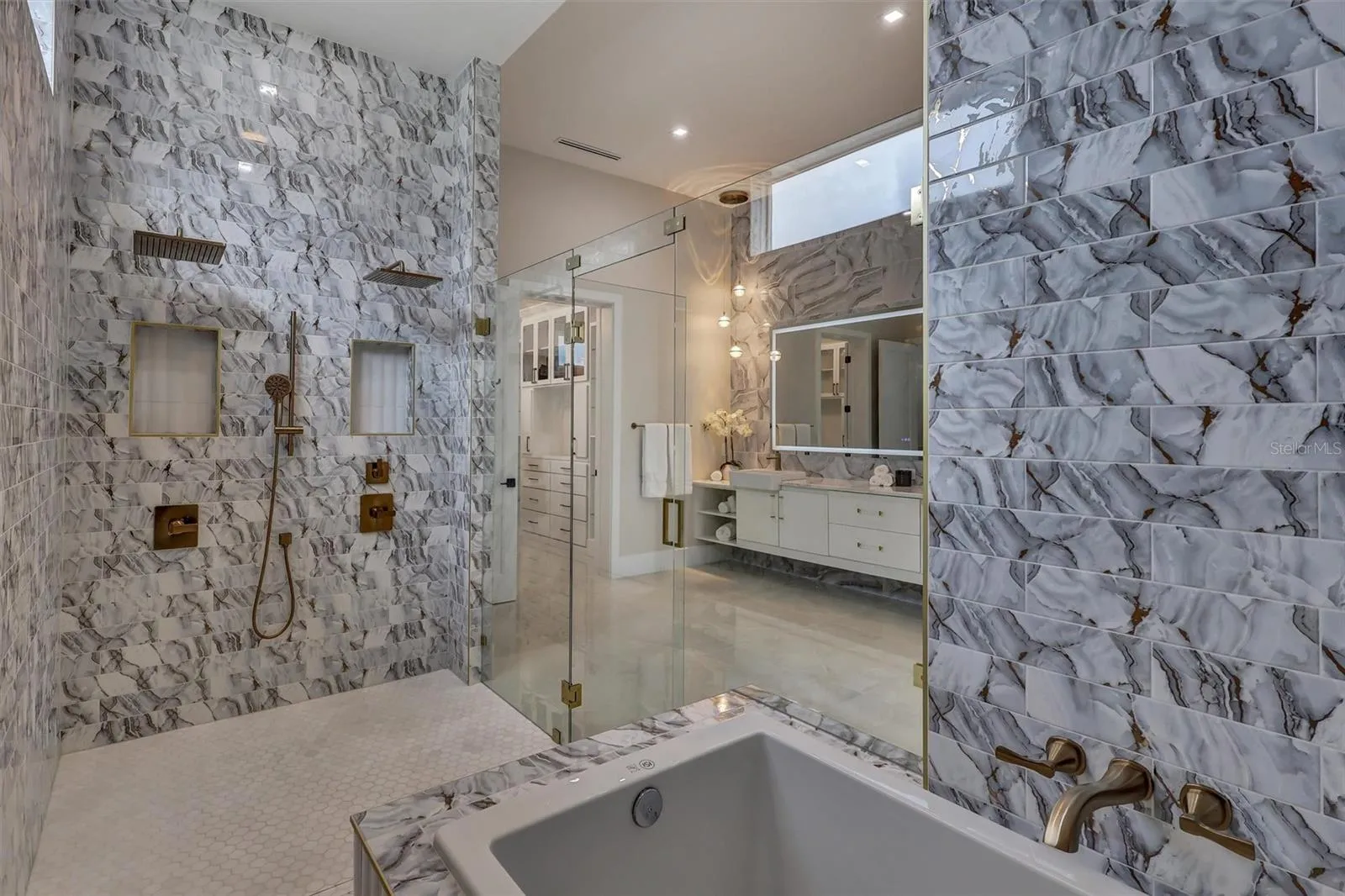 Luxurious soaking tub incorporated within the expansive primary wet room with accompanying built in seat