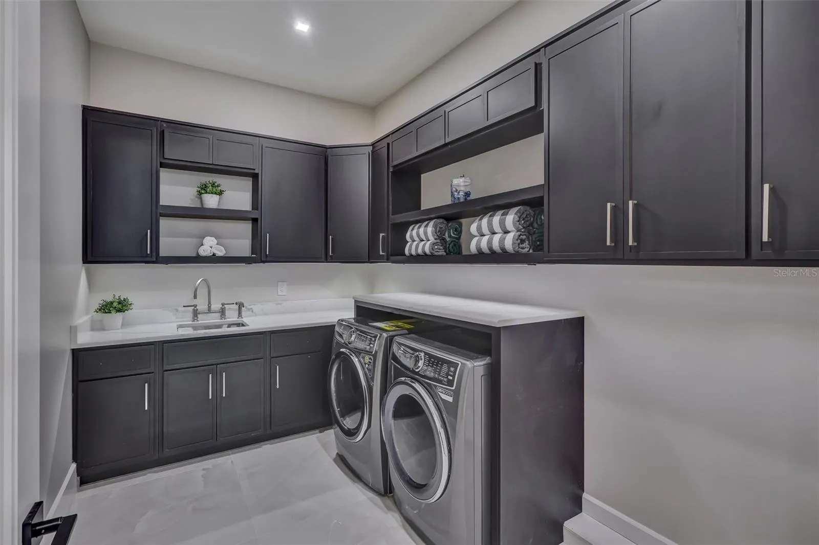 Large dedicated laundry room with extensive cabinetry, undermount lighting and workspace