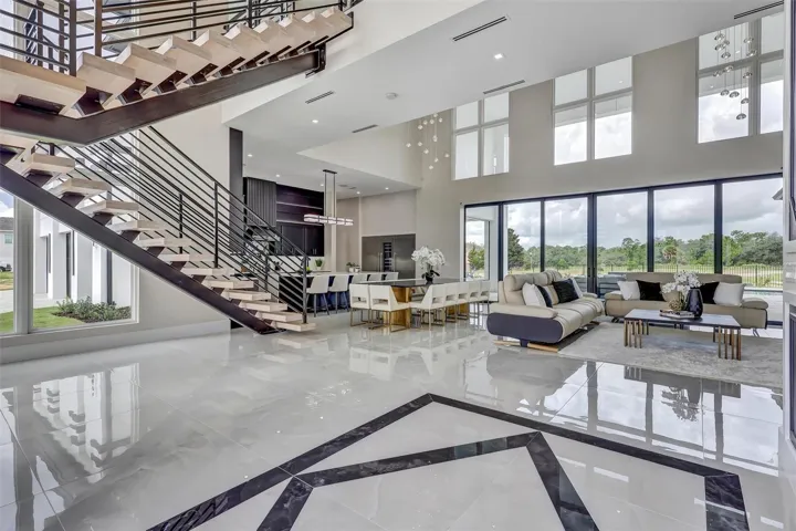 Dramatic open-concept living framed by the floating staircase and walls of glass