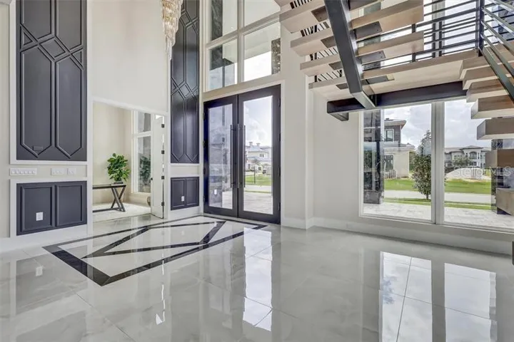 Dramatic entry framed by the floating staircase and two-story windows