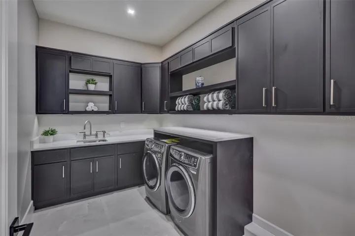 Large dedicated laundry room with extensive cabinetry, undermount lighting and workspace