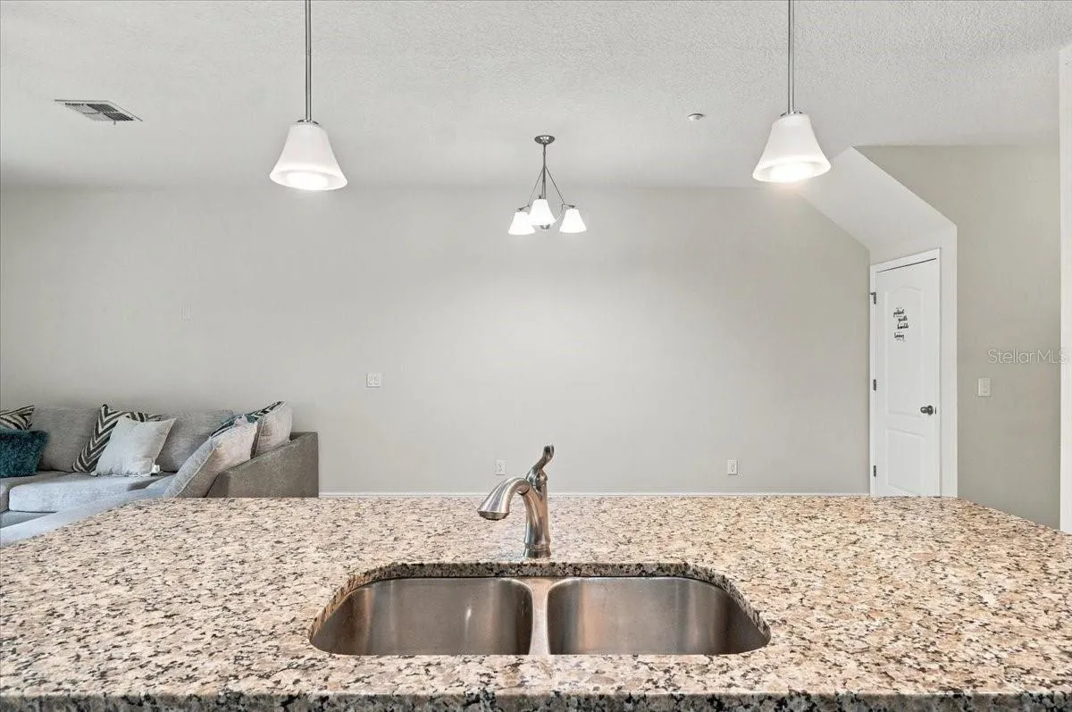 Granite kitchen island with double basin sink and stylish pendant lighting
