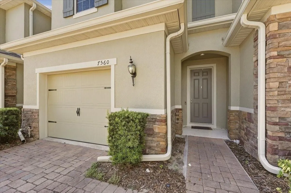 Welcoming entryway with stone detail, covered walkway, and attached one-car garage