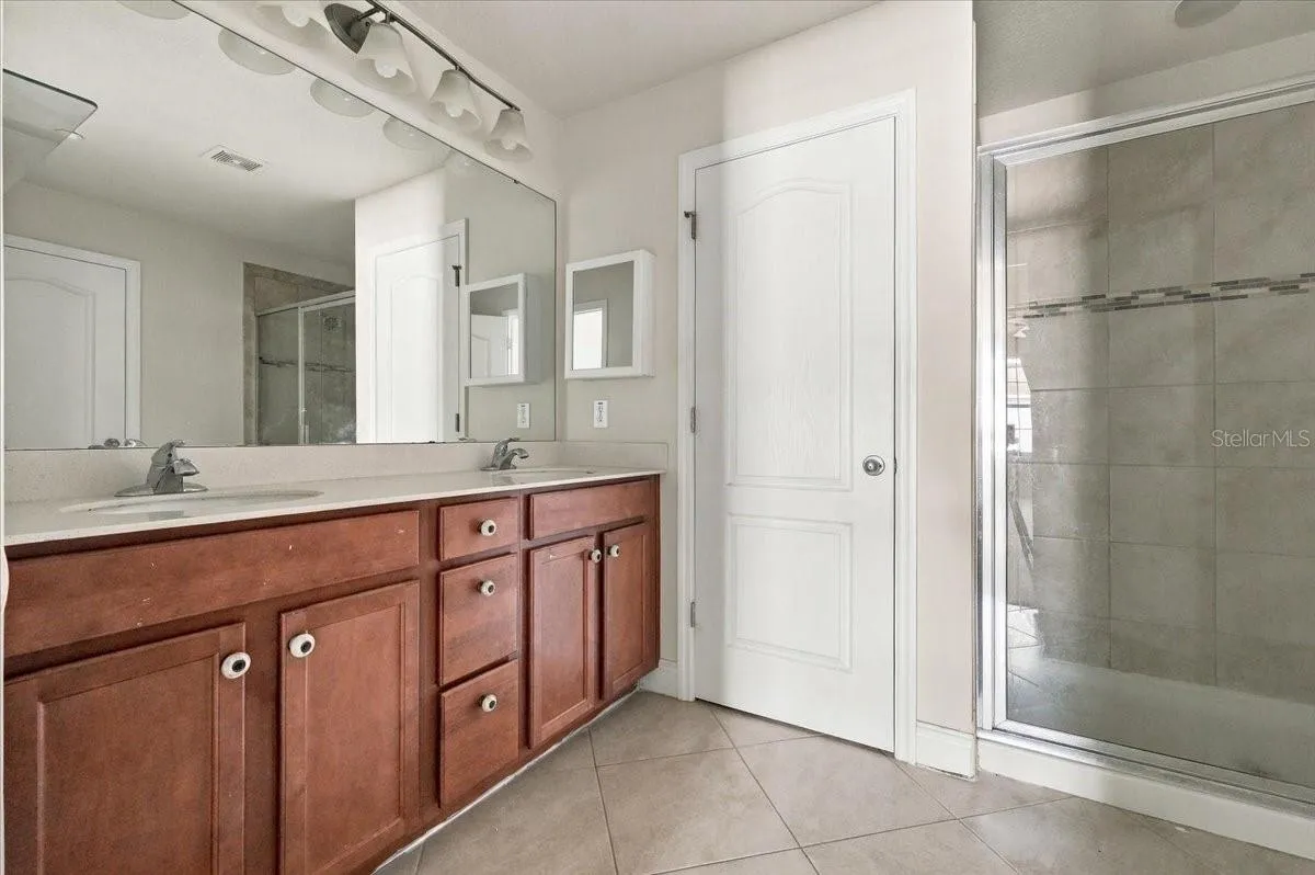 Primary ensuite bath featuring dual-sink vanity and a glass-enclosed walk-in shower