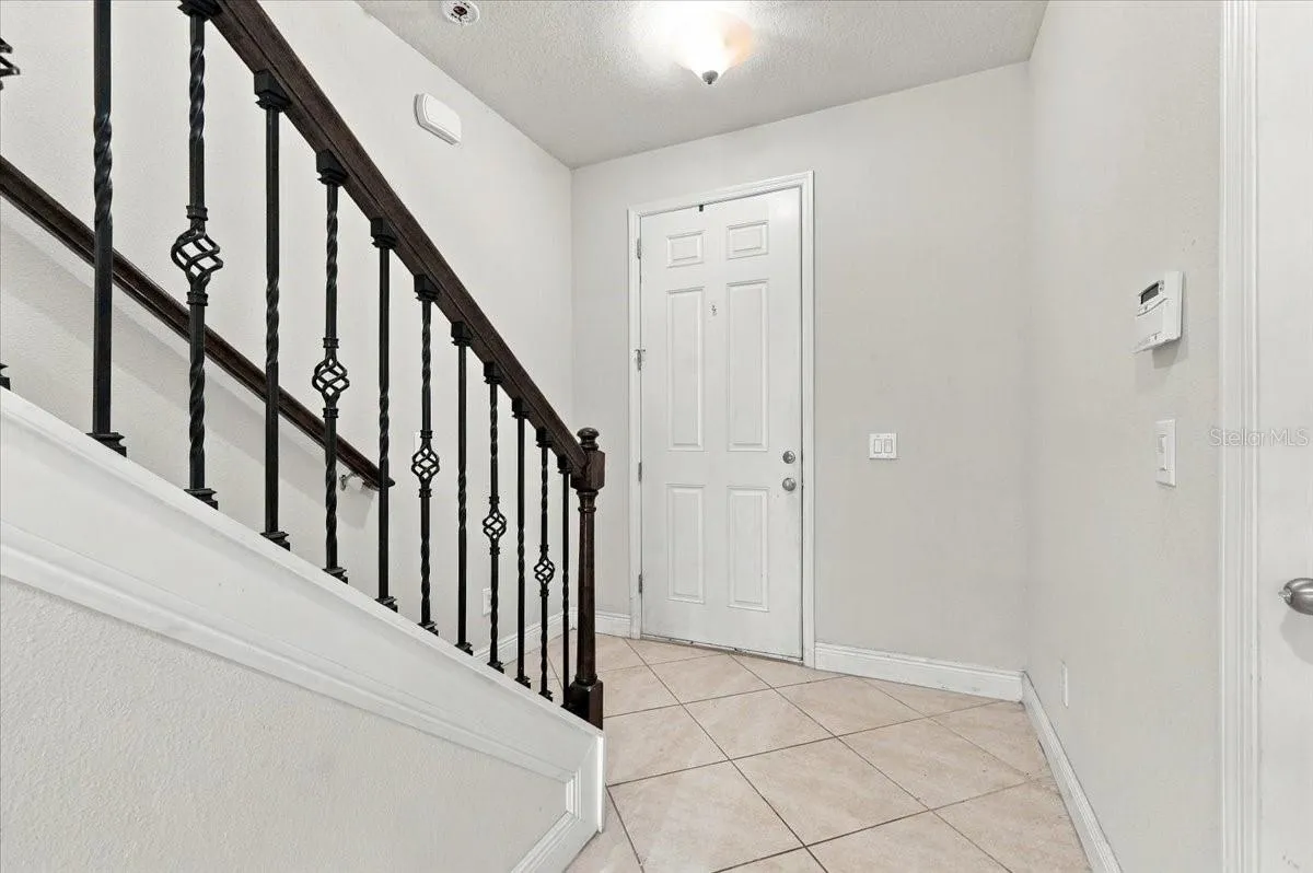 Bright foyer featuring tile flooring and an elegant wrought-iron stair railing