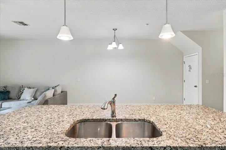 Granite kitchen island with double basin sink and stylish pendant lighting