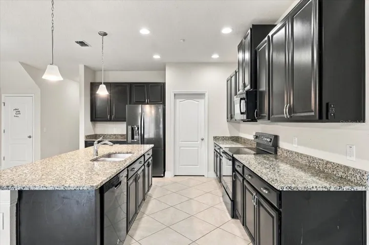 Well-appointed kitchen with rich cabinetry, granite counters, and stainless steel appliances