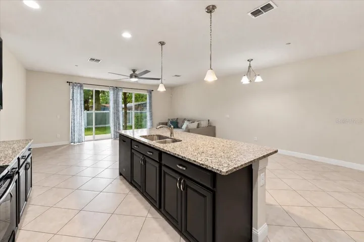 Kitchen island with pendant lighting flows seamlessly into the dining and living space