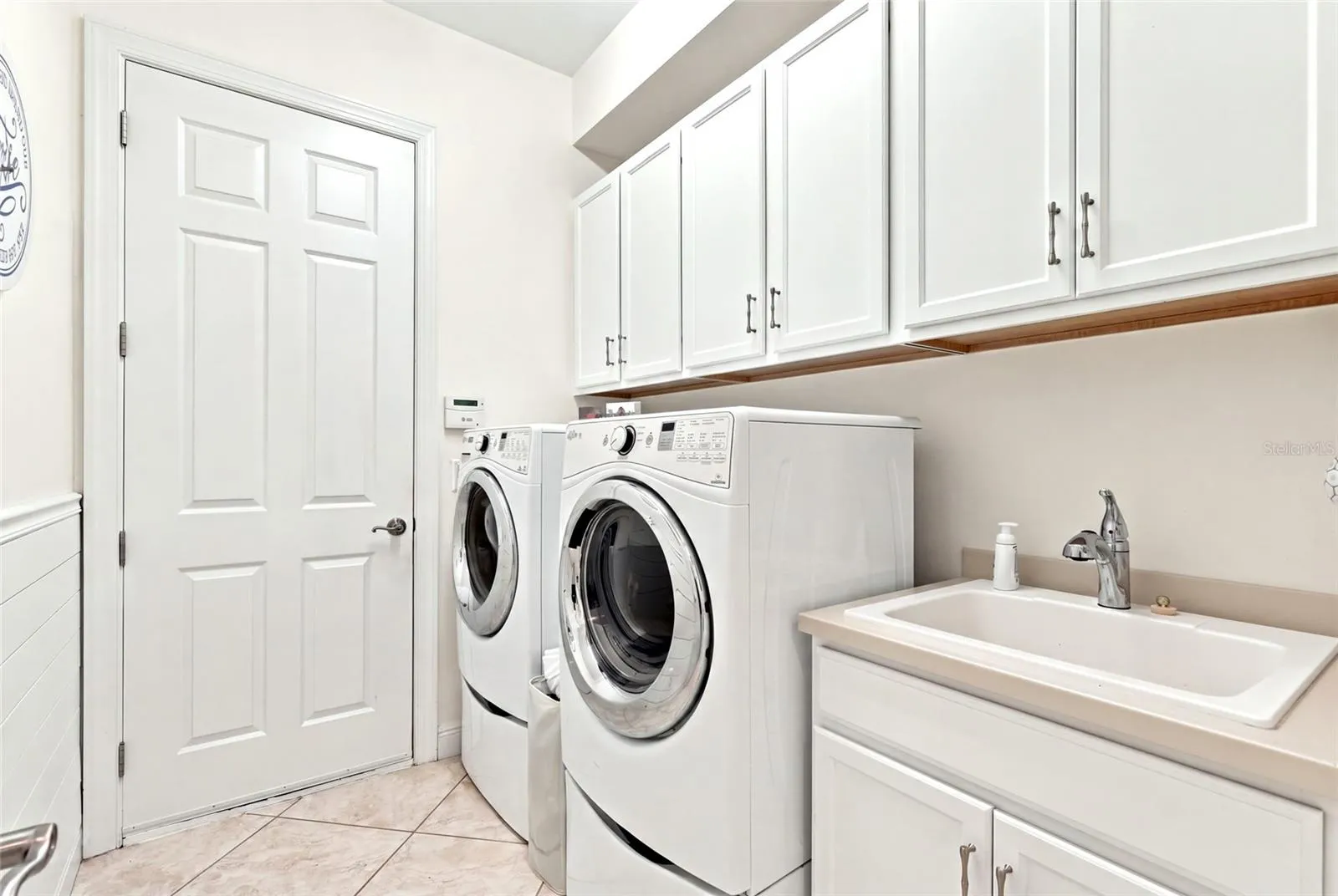 interior laundry room full size washer/dryer cabinetry and laundy sink