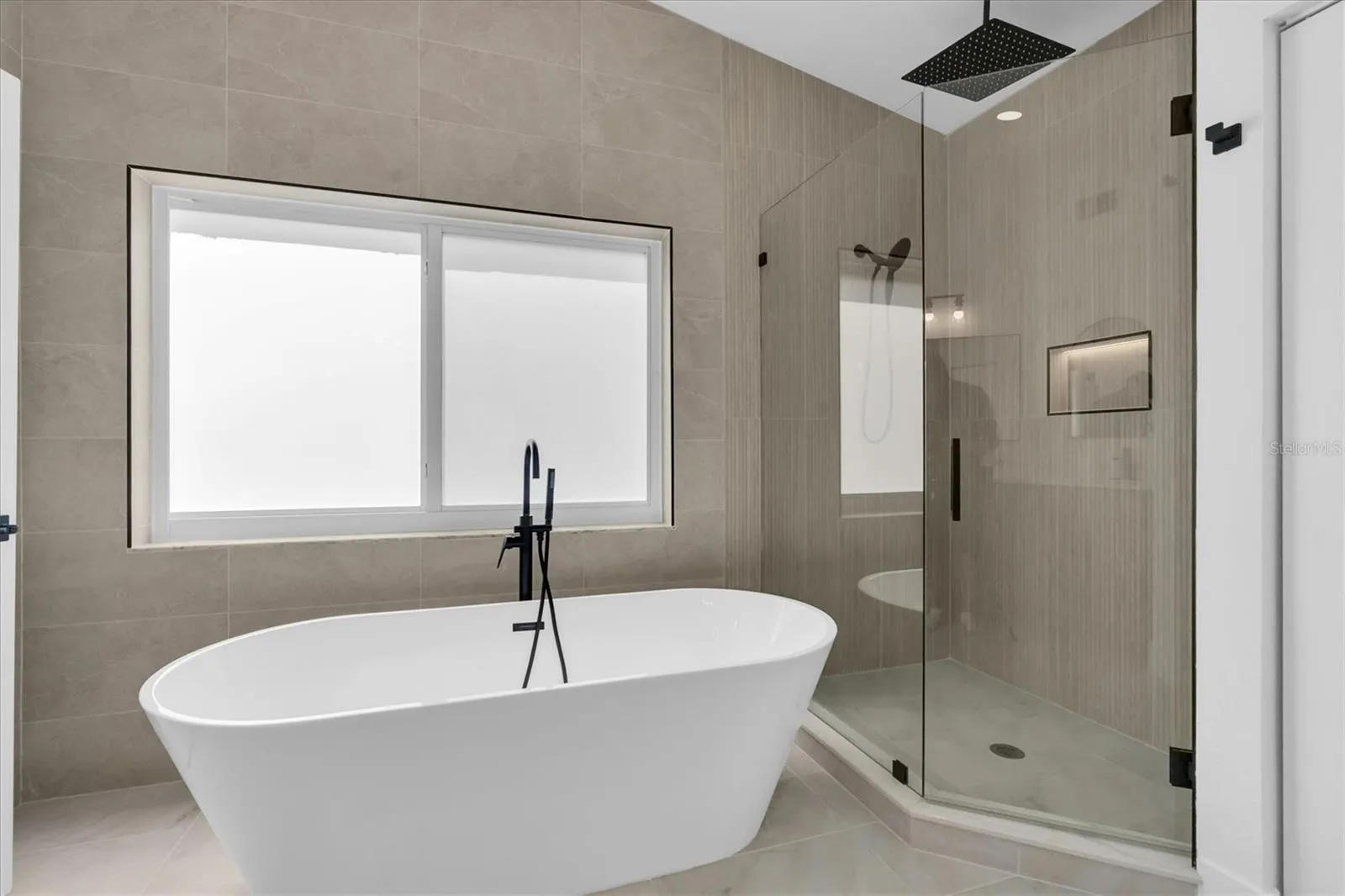 Spa-inspired primary bath with freestanding soaking tub and oversized walk-in shower.
