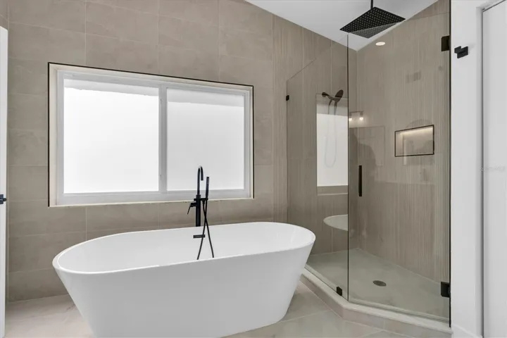 Spa-inspired primary bath with freestanding soaking tub and oversized walk-in shower.