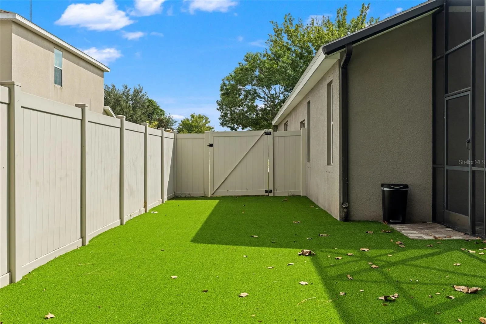 More pet-safe turf continues along the side of the home, maximizing usable fenced space while keeping yard maintenance simple.