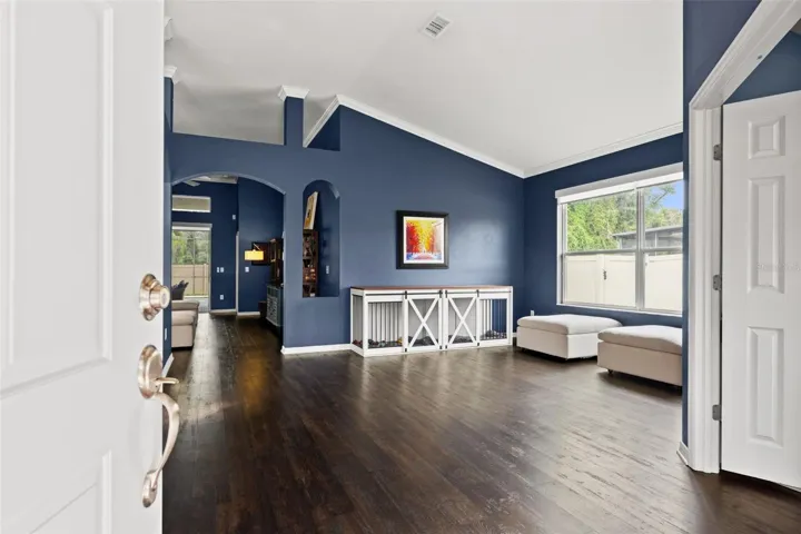 Step inside to a bright, open interior where high ceilings and rich flooring immediately create a sense of space.