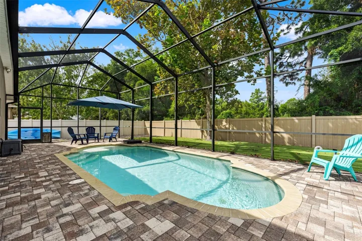 A spacious paver pool deck provides plenty of room for loungers, conversation areas, and entertaining around the water.