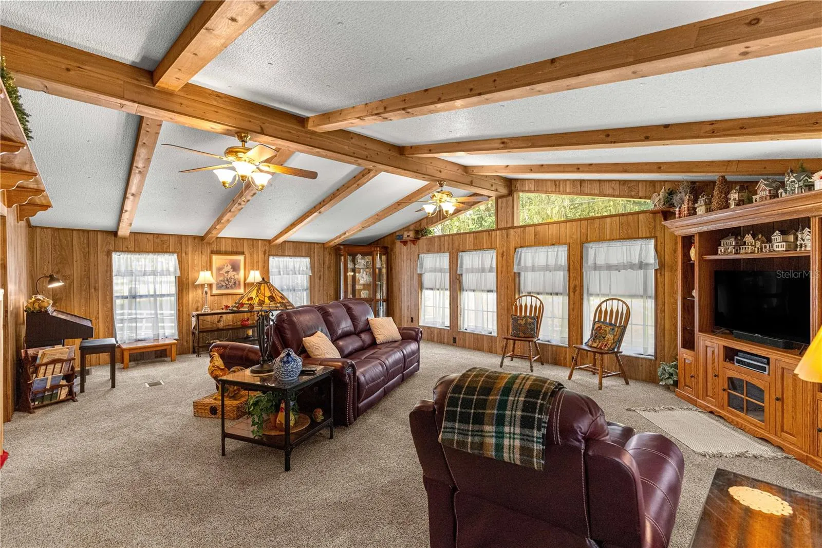 Living room with wood paneling and a wall of windows.