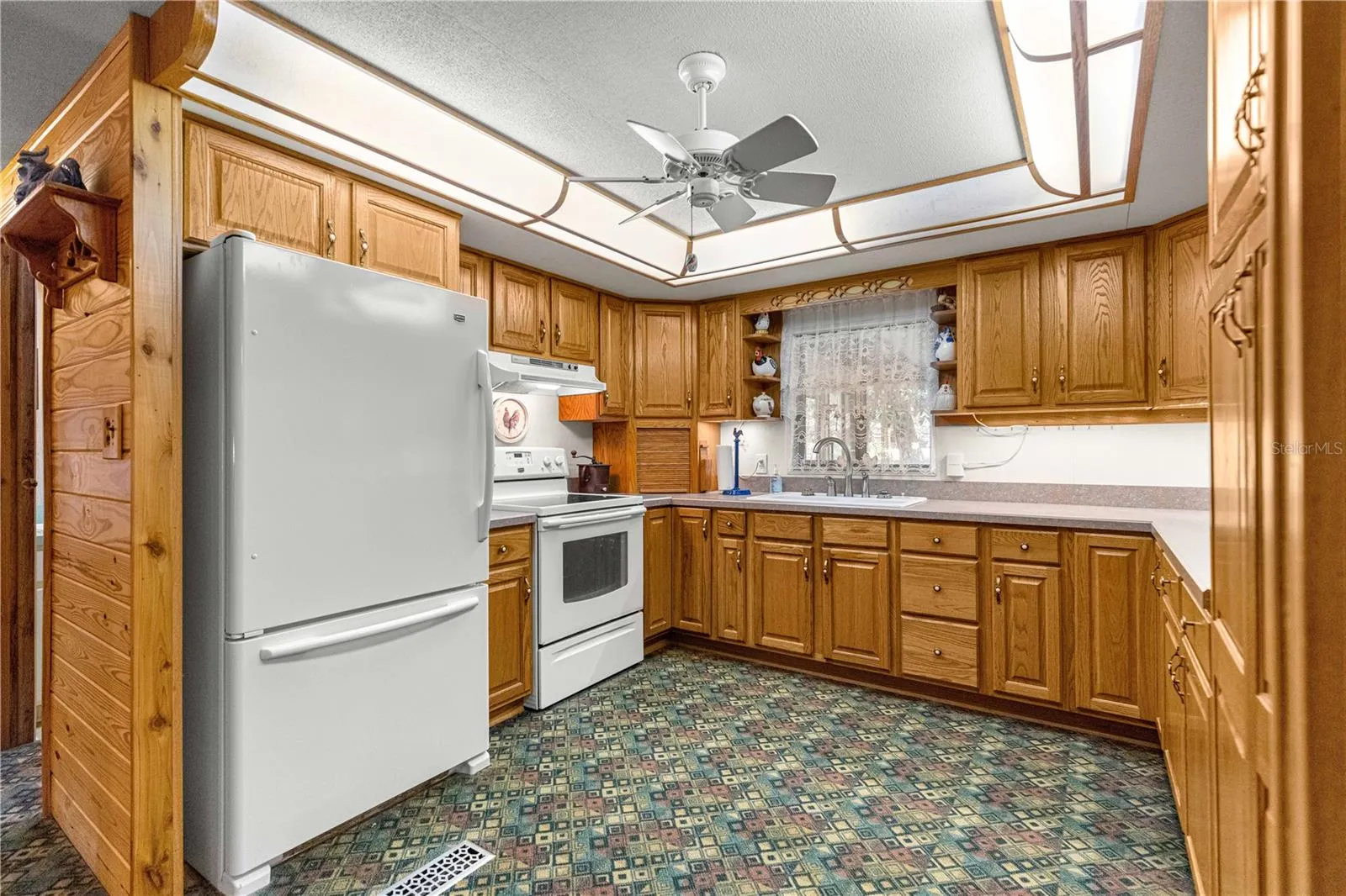 Kitchen with wood cabinetry and window above the sink.
