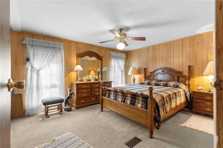 Bedroom with wood-paneled walls and two windows.