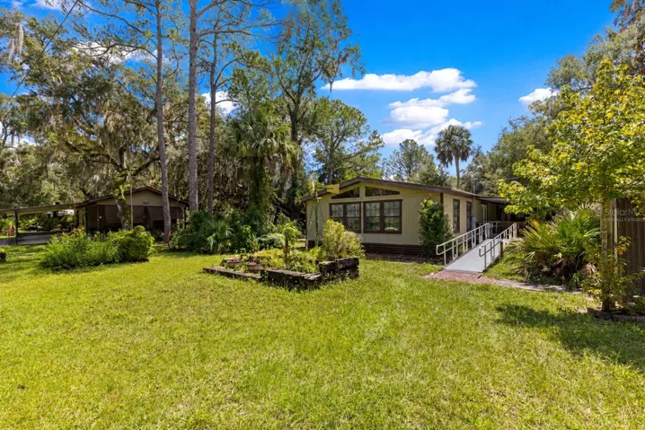 #1 · Main residence and ramp approach, with mature trees and lawn. Virtually staged—personal items digitally removed.