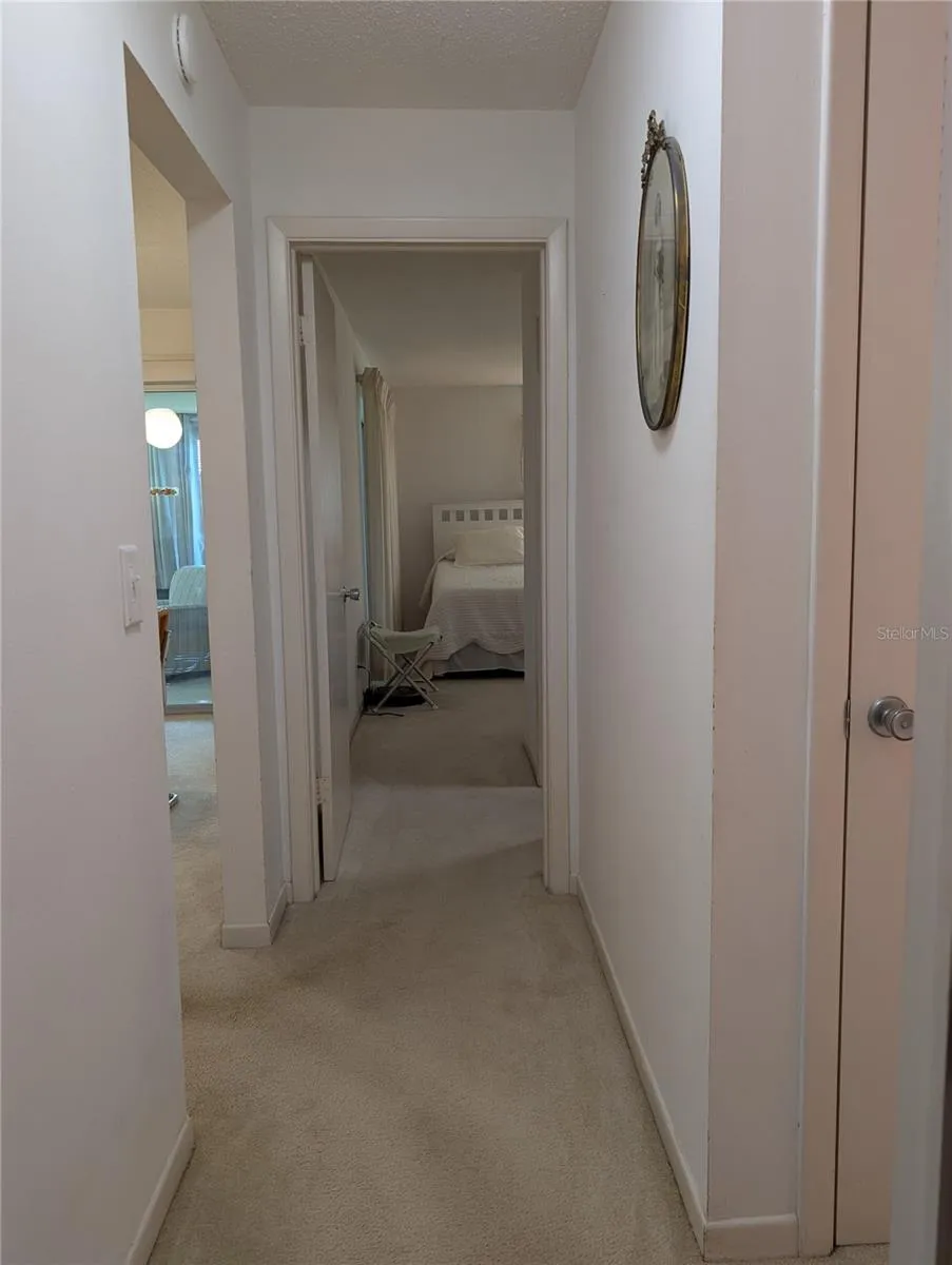 View from guest bedroom down hallway to primary bedroom with ensuite bath.  Linen closet at entry to main bathroom on right.  Living area on left.