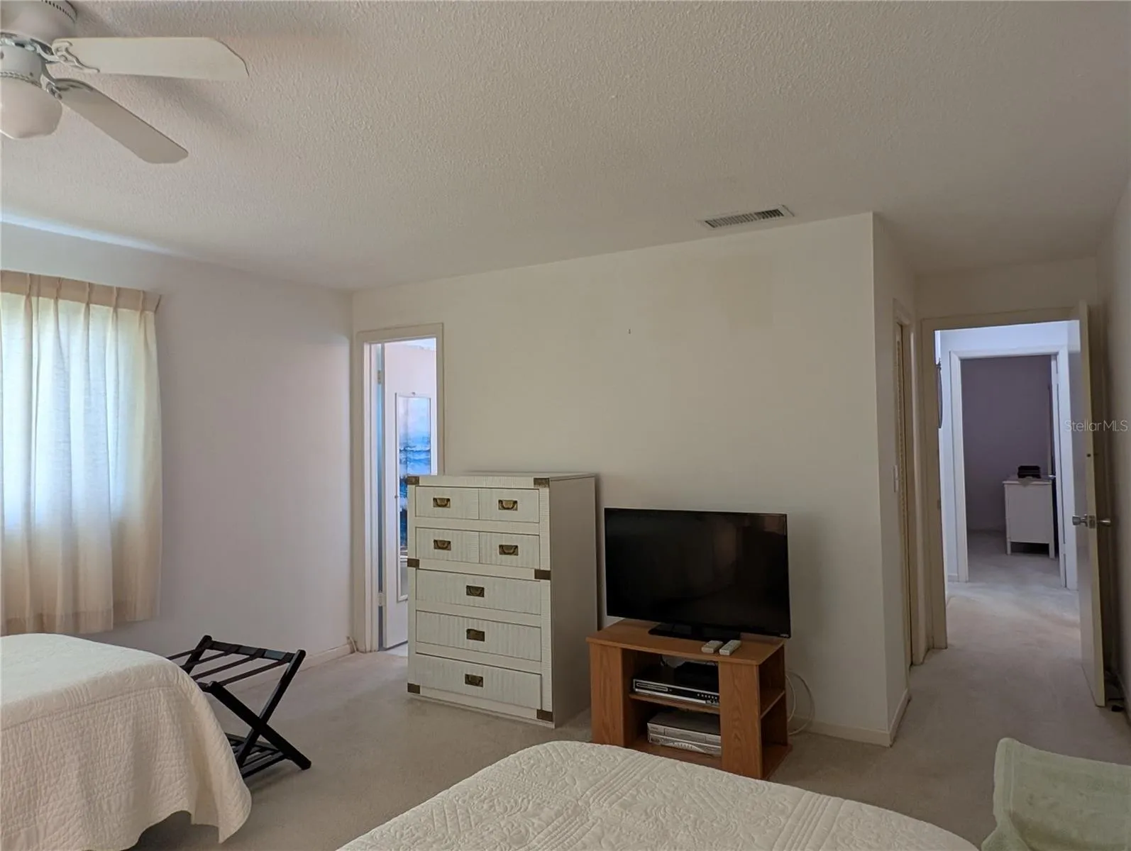 View from primary bedroom down hallway to guest bedroom.  Closet entry visible to left of bedroom door.